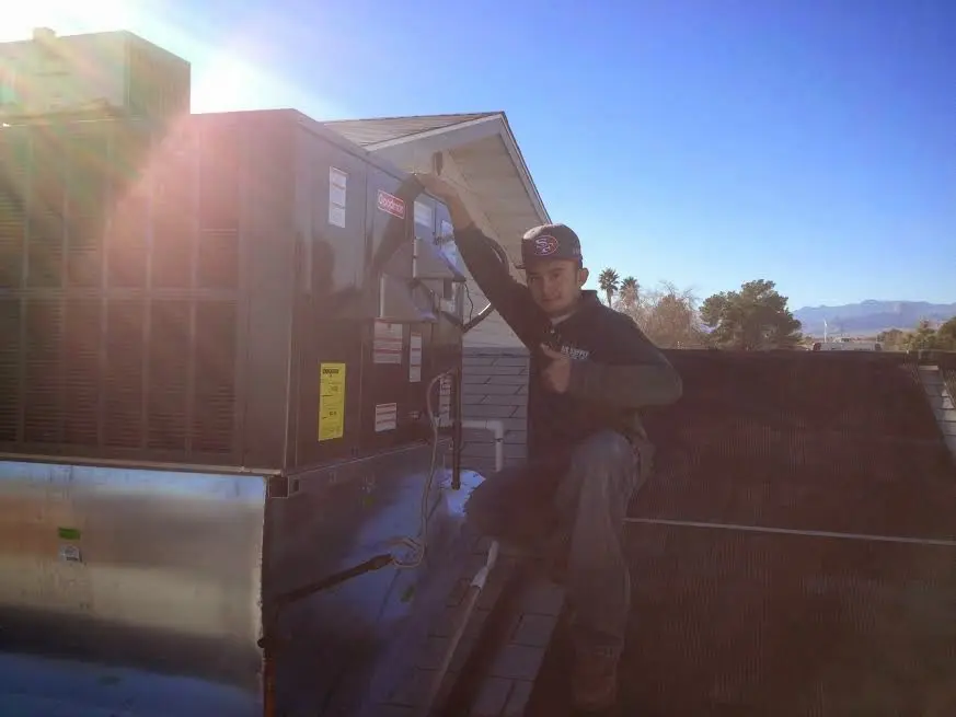 HVAC technician performing Heat Pump Repair on a rooftop unit in Harrah
