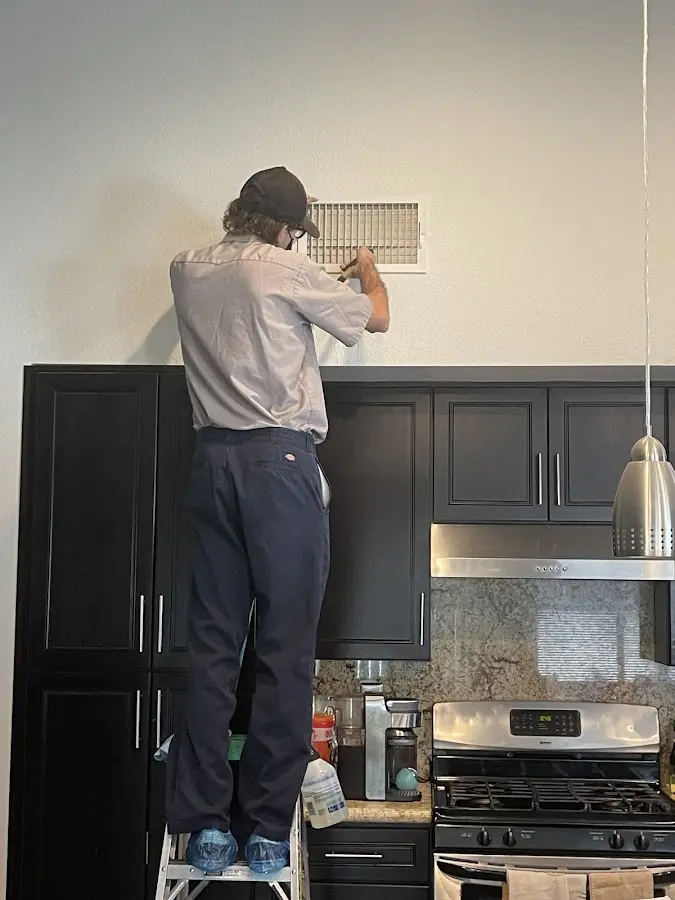 Technician inspecting an air vent during HVAC service in Harrah